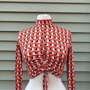 Orange and black geometric print long sleeve top with tie front and high neck